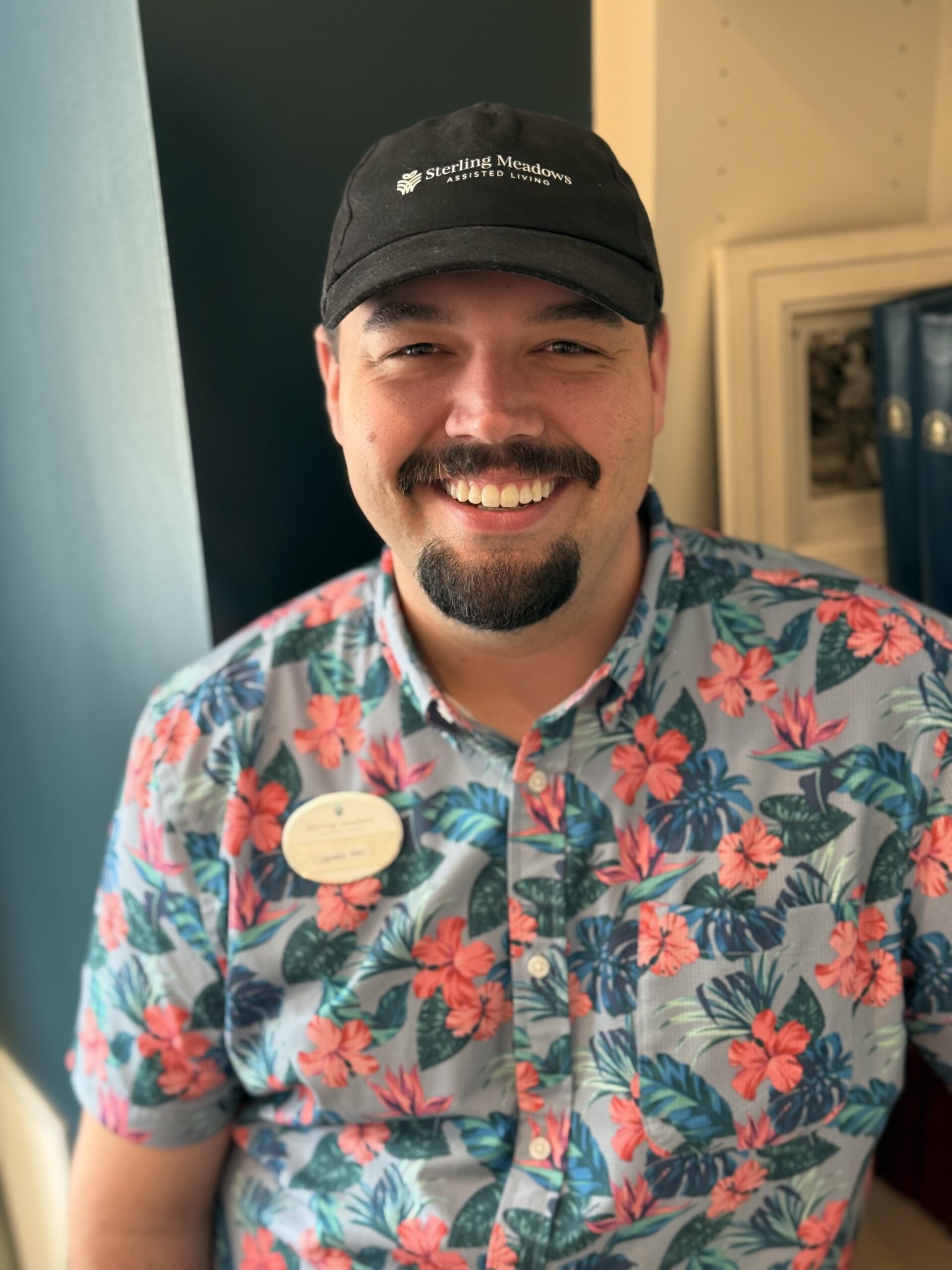 Staff member smiling in floral shirt indoors