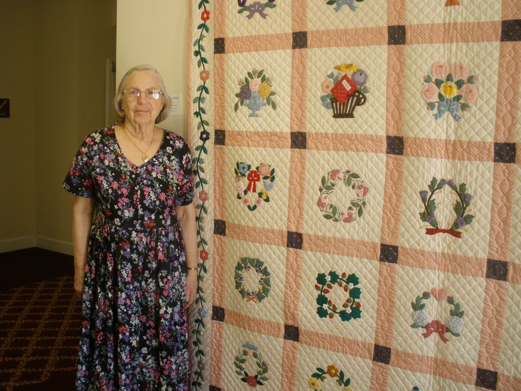 A resident stands by a colorful quilt in the facility