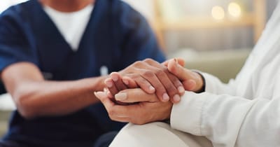 Caregiver holding a resident's hands in a supportive manner