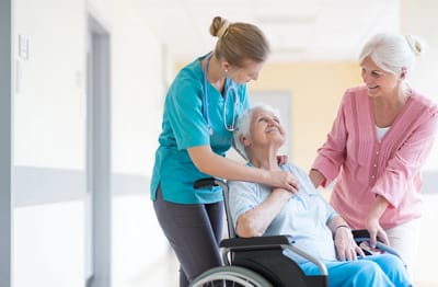 Staff assisting a smiling resident in a hallway