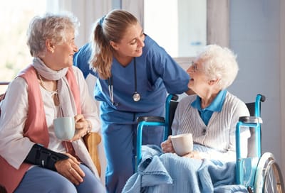 Woodridge Village, Nursing Home in South Bend, IN — Caregiver interacting with two senior residents in a lounge