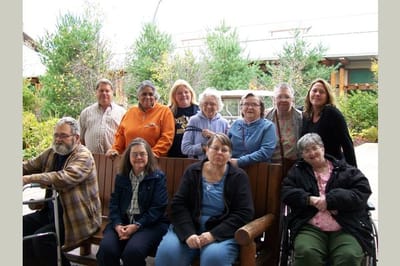 Residents and staff posing together in a garden area