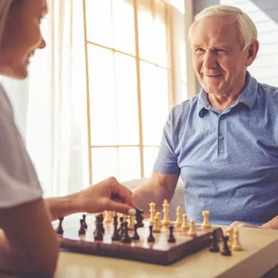 Two people playing chess in a bright room