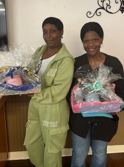 Two staff members holding gift baskets