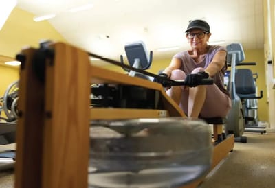 Resident exercising on a rowing machine in the fitness center