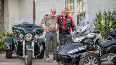 Two residents standing beside motorcycles outdoors