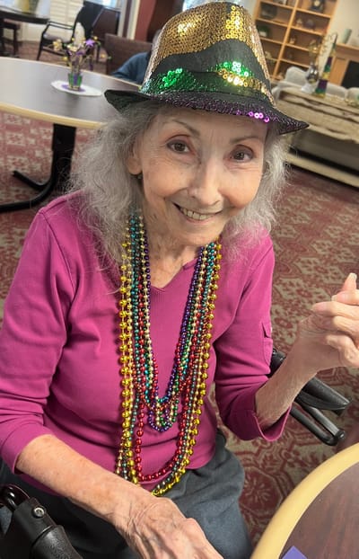 Resident celebrating with beads and a hat in the common area