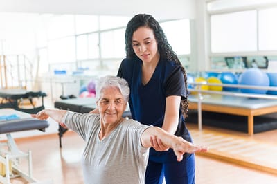 Therapist assisting an elderly woman during physical therapy