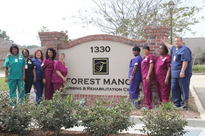 Staff members posing in front of the facility sign