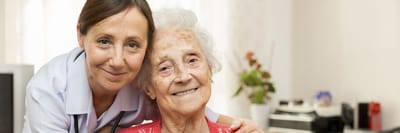 A caregiver and an elderly resident smiling together