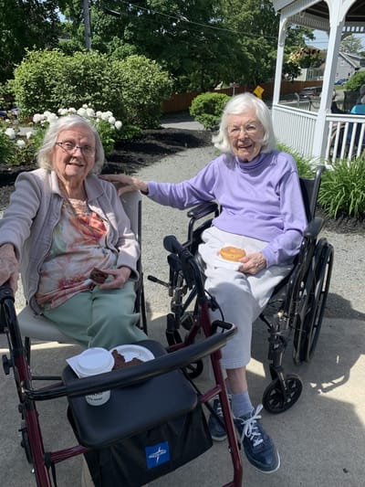 Two residents enjoying snacks outside on a sunny day