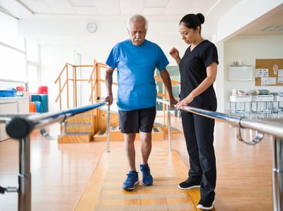 An elderly man receiving assistance during therapy