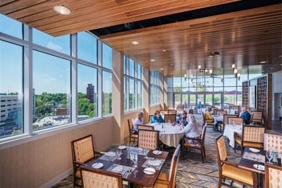 Residents dining in a sunlit dining area with large windows