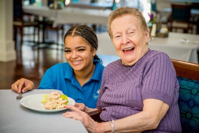 Resident enjoying a meal with a staff member