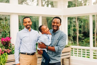 Two men and a boy smiling in a bright interior space