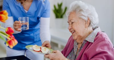 Caregiver serving snacks to a smiling resident