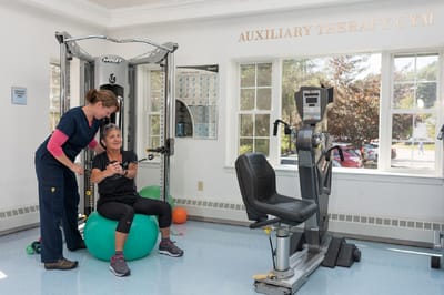Residents exercising with staff guidance in a therapy gym