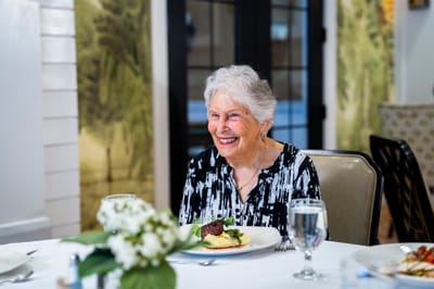 A smiling resident enjoying a meal in the dining room
