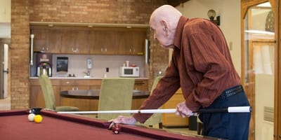 A resident playing pool in an activity room