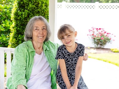 Senior resident smiling with a young girl in a garden