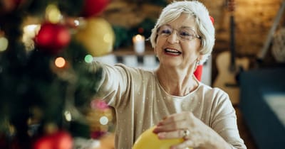 Senior woman decorating a Christmas tree