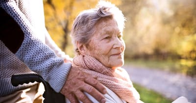 An elderly woman enjoying a stroll outdoors with assistance