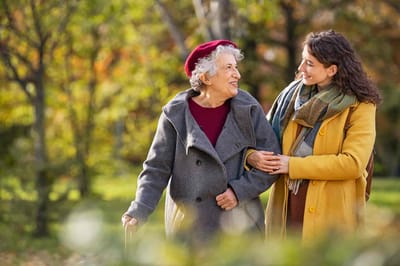 Two women walking in a garden area during fall