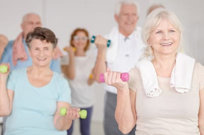 Senior residents exercising with dumbbells in an activity room
