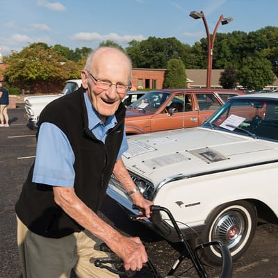 Elderly man with a bicycle at an outdoor car show