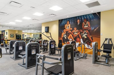 Fitness area with exercise machines and sports mural