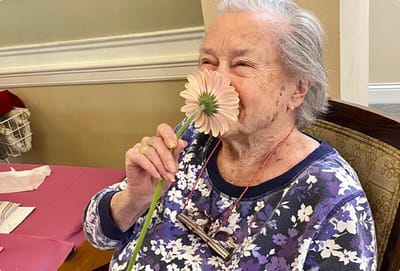 Resident smiling with a flower in a common area