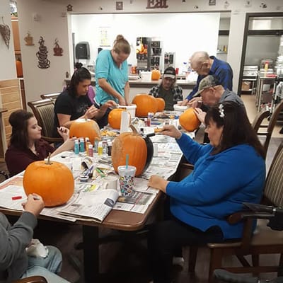 Residents and staff decorating pumpkins in a common area
