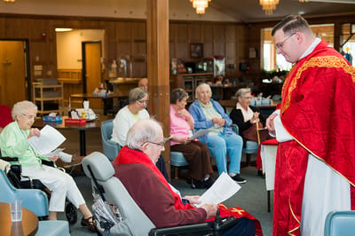 Residents participating in a gathering with a priest
