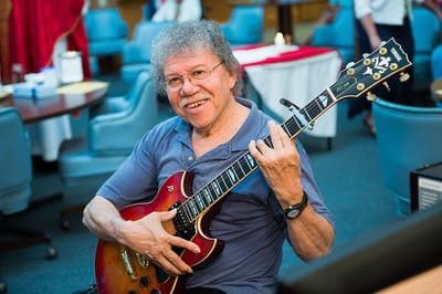 Resident playing guitar in a lively indoor setting