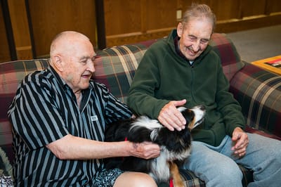 Two residents interacting with a dog in a common area
