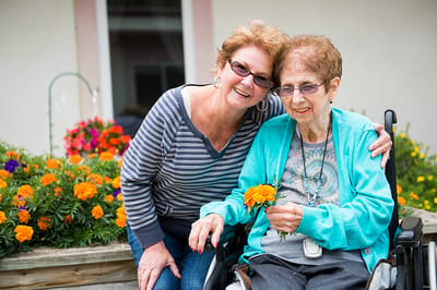 Resident and staff member in a flower garden