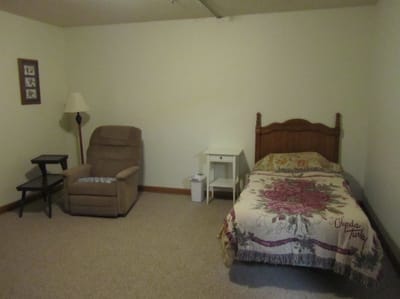 A private resident room with a bed and chair