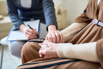 Caregiver and resident holding hands during a conversation