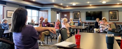 Seniors participating in a seated exercise class