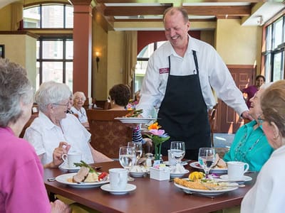 Residents enjoying a meal with staff in a dining area