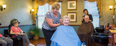 Residents receiving haircuts in an activity room