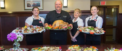 Staff serving a festive meal with a turkey centerpiece