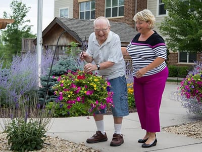 A senior man gardening with assistance from a staff member