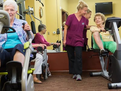 Residents exercising with staff in a gym area