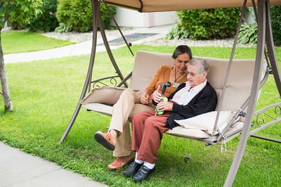 A resident and staff member enjoying time outside on a swing