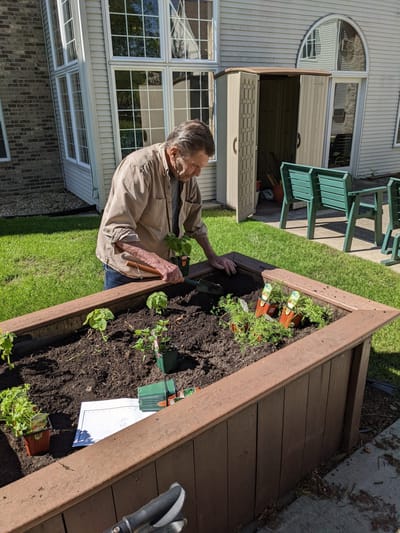 Resident gardening in an outdoor raised bed