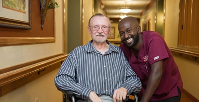 Smiling resident with staff member in a corridor