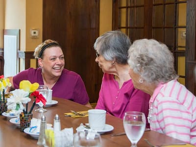 Residents enjoying a meal and conversation with staff