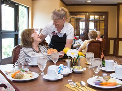 Staff serving food to a resident in the dining area