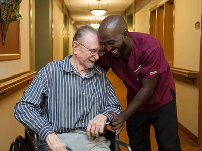 A staff member laughing with a resident in a hallway